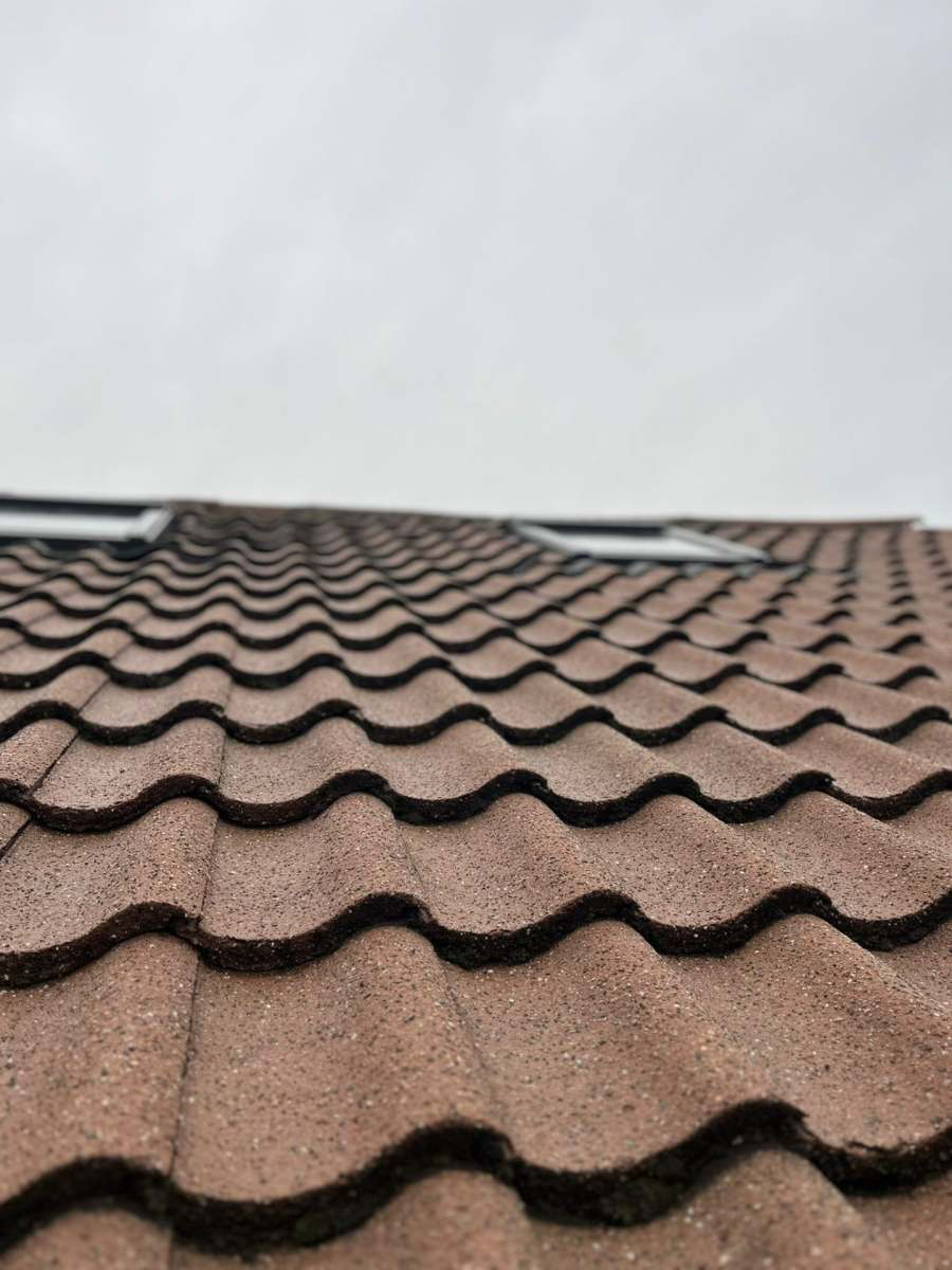 Clean reddish-brown roof tiles after professional moss removal
